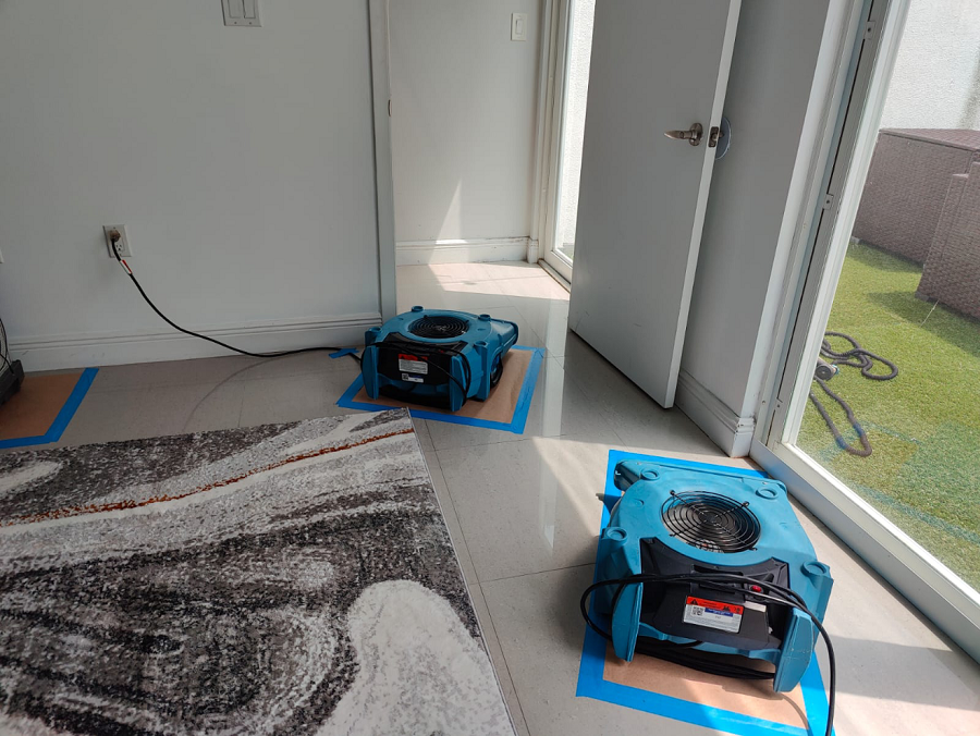Emergency water removal service extracting standing water from a flooded Miami home